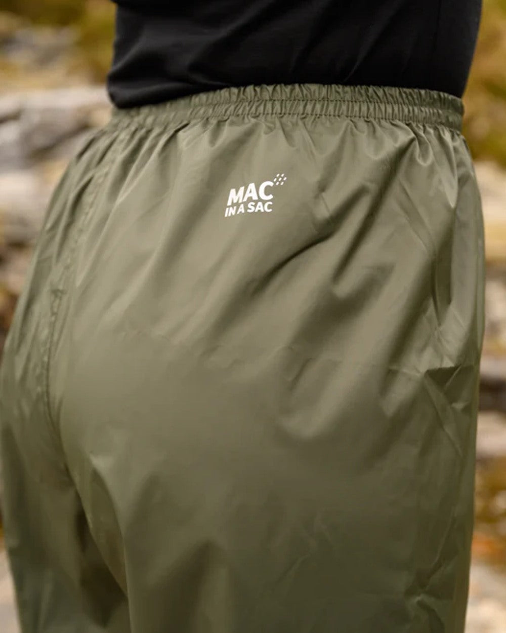 khaki coloured Mac In A Sac Origin Packable Waterproof Overtrousers on blurry background 