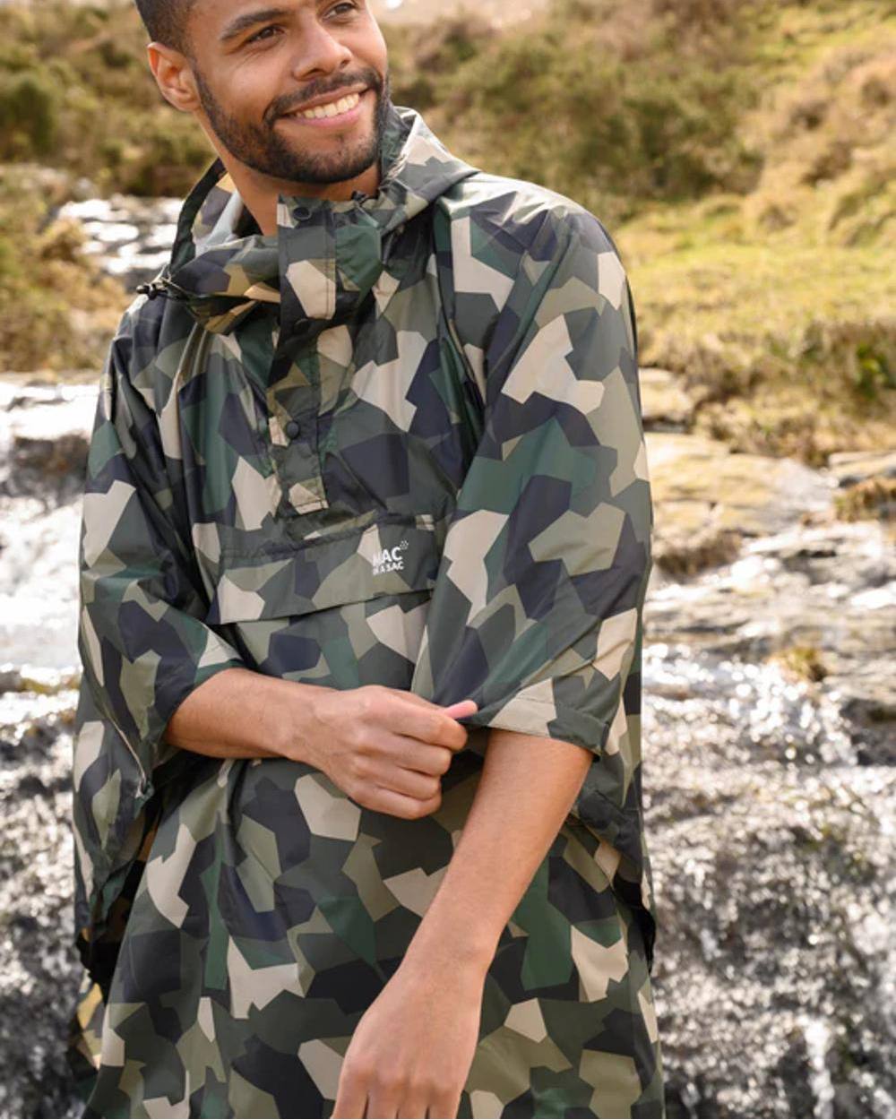 Green Camo Coloured Mac In A Sac Origin Waterproof Poncho on blurry background 