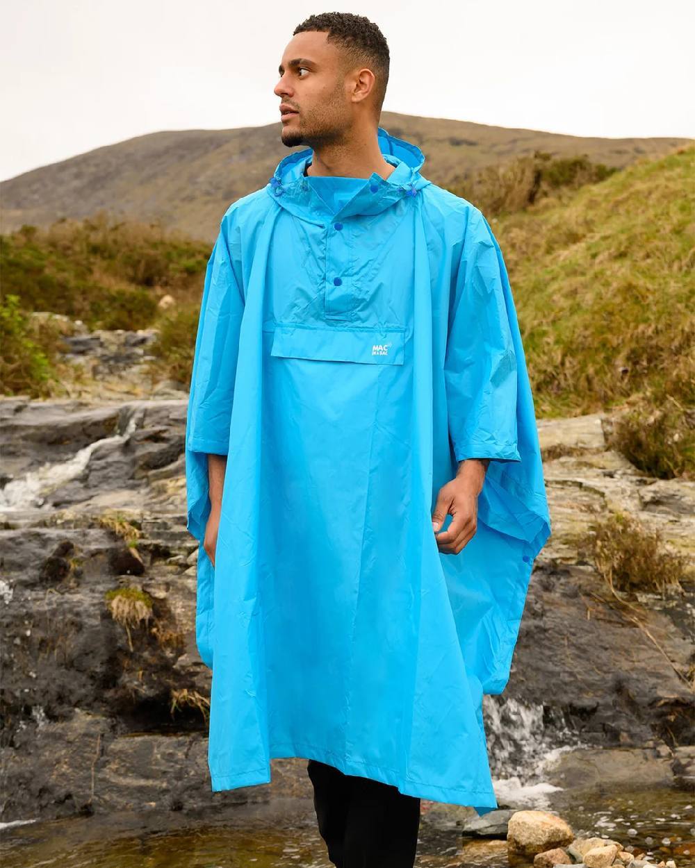 Neon Blue Coloured Mac In A Sac Origin Waterproof Poncho Neon on mountain background 