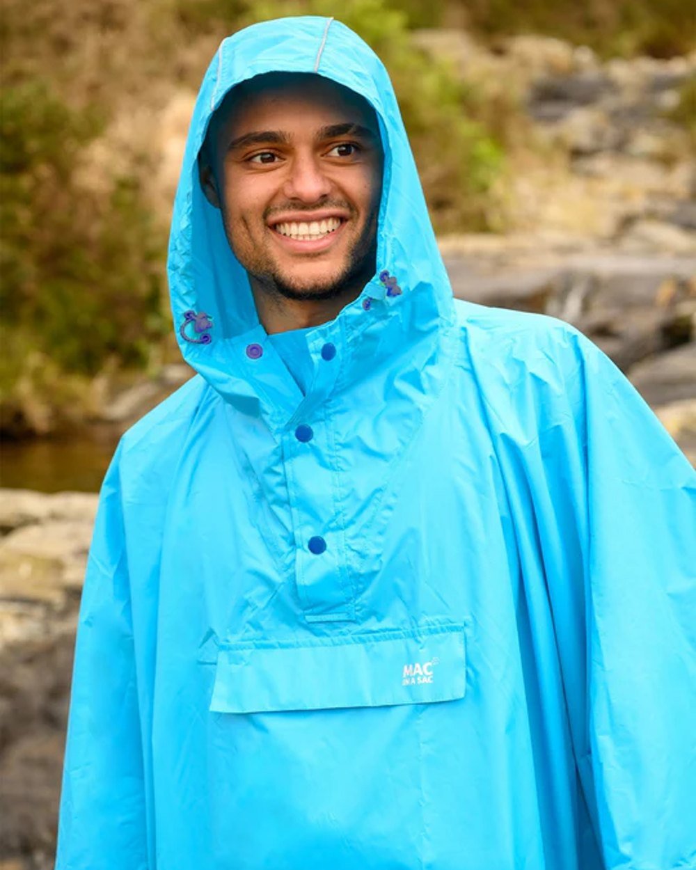 Neon Blue Coloured Mac In A Sac Origin Waterproof Poncho Neon on blurry background 