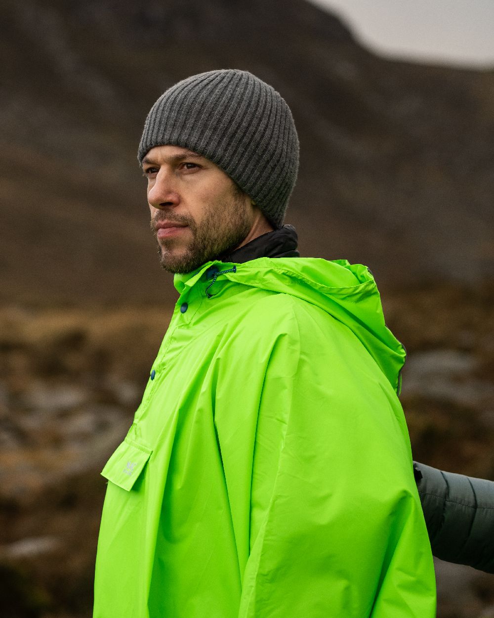 Neon Green Coloured Mac In A Sac Origin Waterproof Poncho Neon on blurry background 
