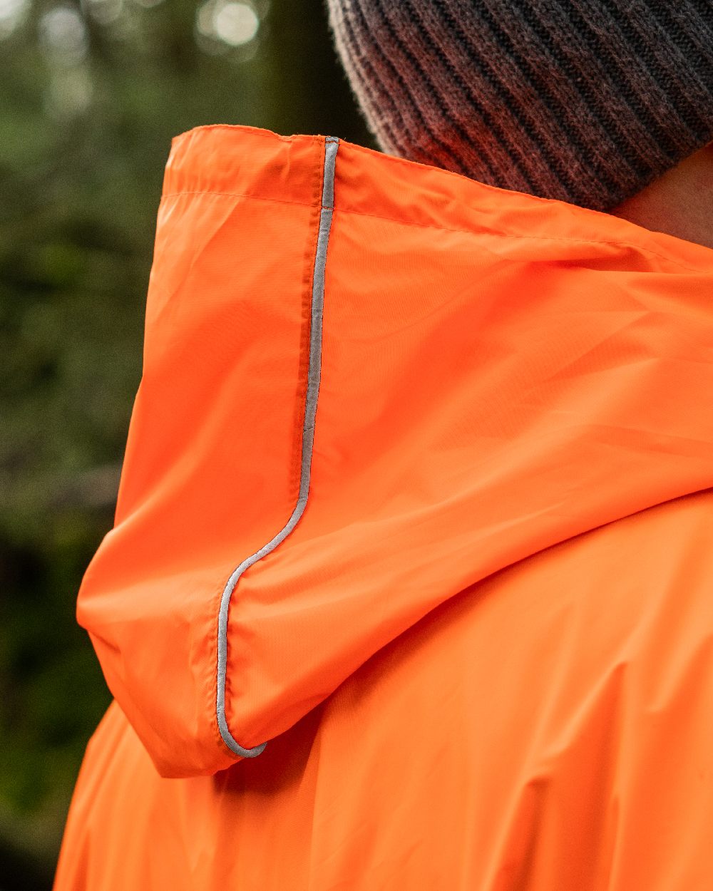 Neon Orange Coloured Mac In A Sac Origin Waterproof Poncho Neon on blurry background 
