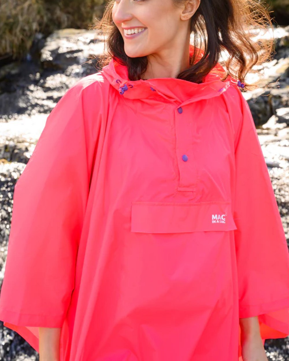 Neon Watermelon Coloured Mac In A Sac Origin Waterproof Poncho Neon on blurry background 