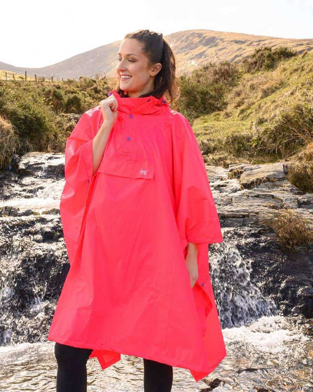 Neon Watermelon Coloured Mac In A Sac Origin Waterproof Poncho Neon on mountain background 