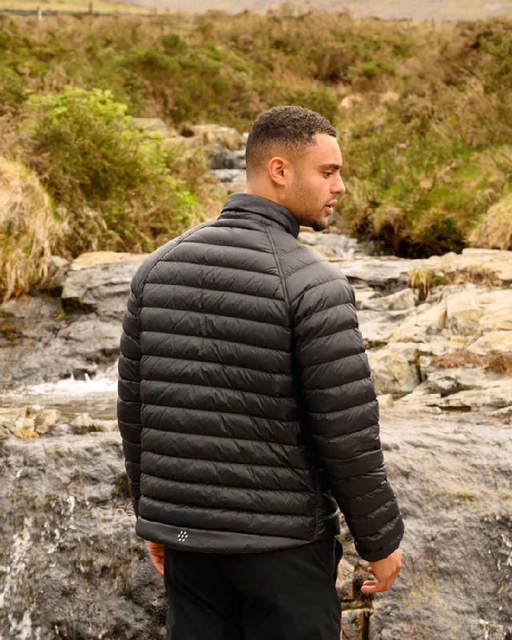 Khaki Black coloured Mac In A Sac Packable Mens Polar Down Jacket on blurry green background 