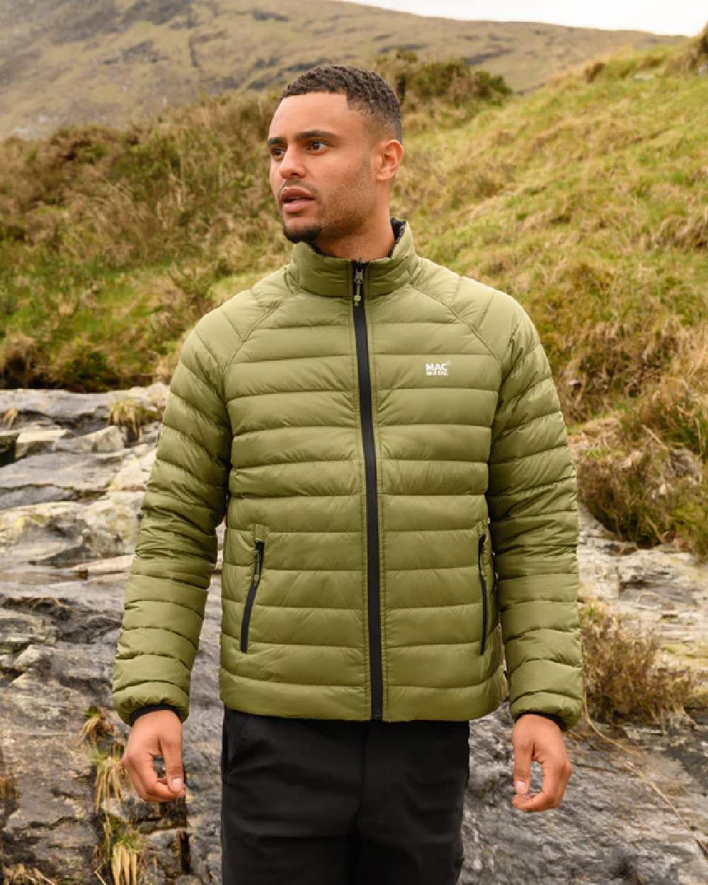 Khaki Black coloured Mac In A Sac Packable Mens Polar Down Jacket on blurry green background 