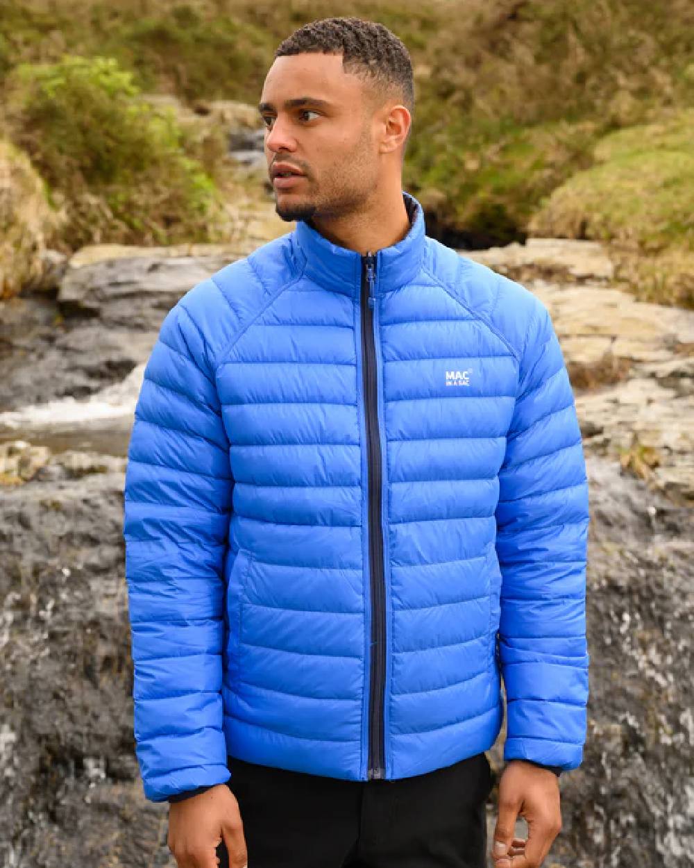 Navy Saxe Blue coloured Mac In A Sac Packable Mens Polar Down Jacket on blurry green background 