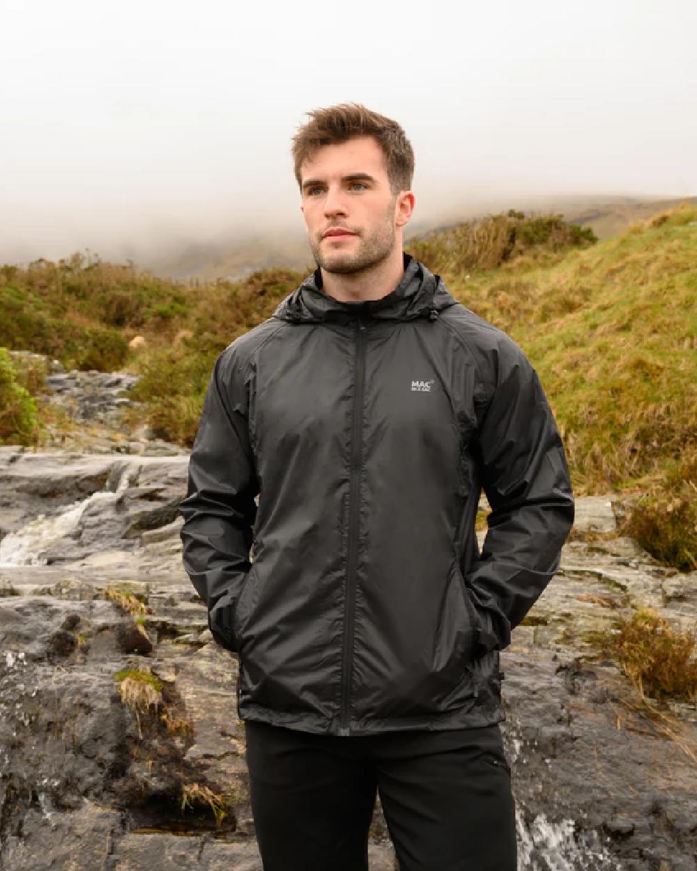 Jet Black coloured Mac In A Sac Packable Origin Waterproof Jacket on blurry background 