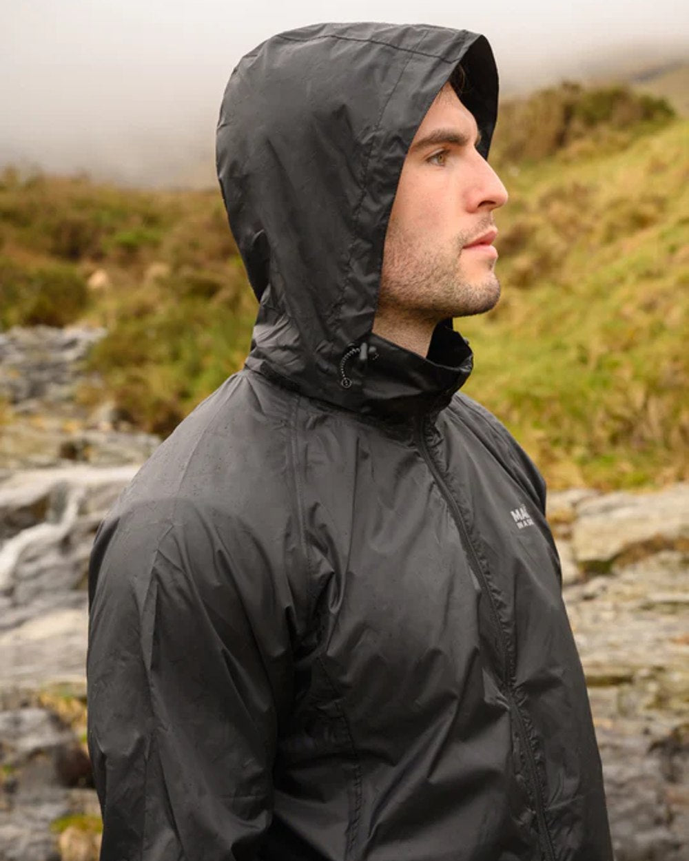 Jet Black coloured Mac In A Sac Packable Origin Waterproof Jacket on blurry background 