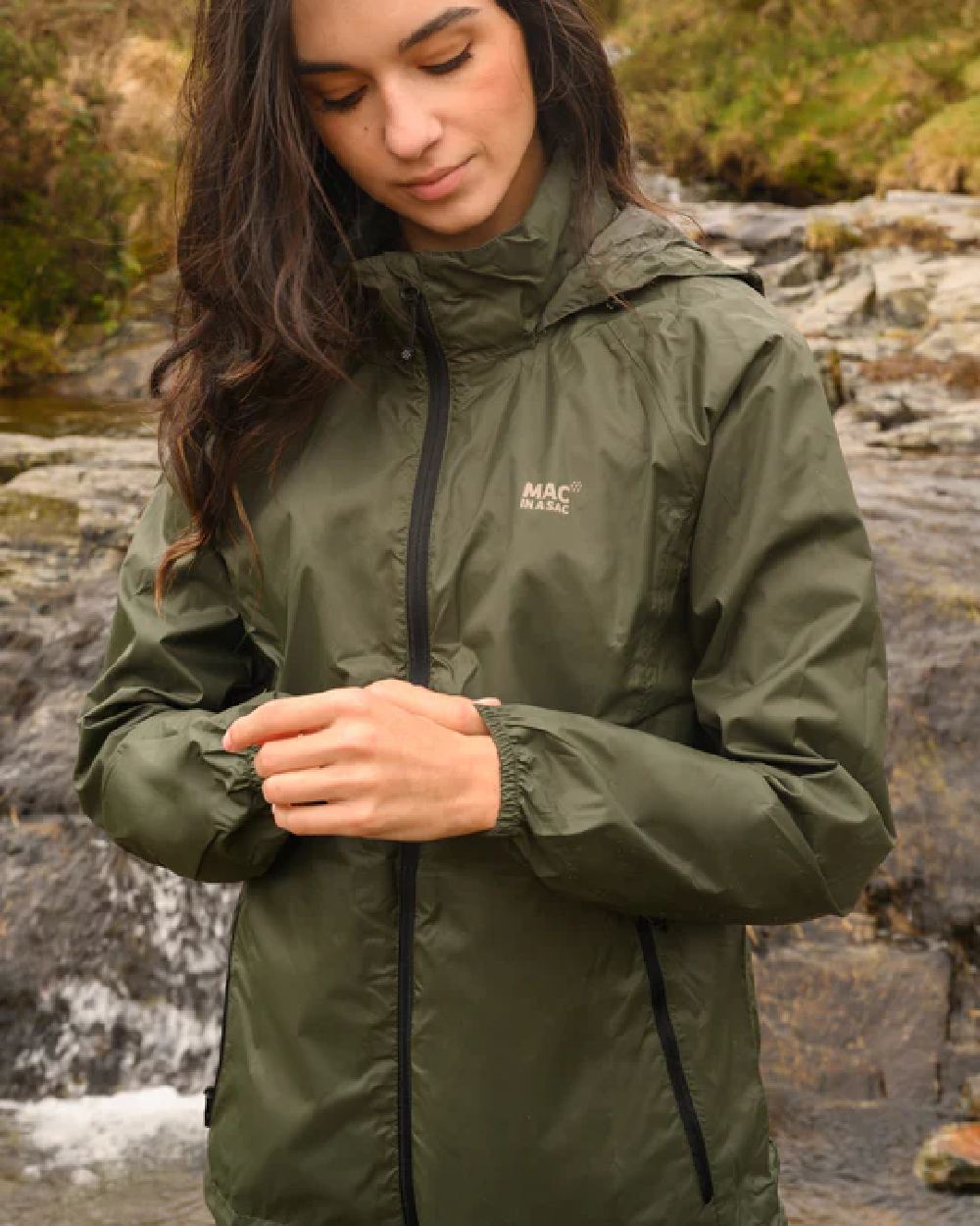 Khaki coloured Mac In A Sac Packable Origin Waterproof Jacket on blurry background 