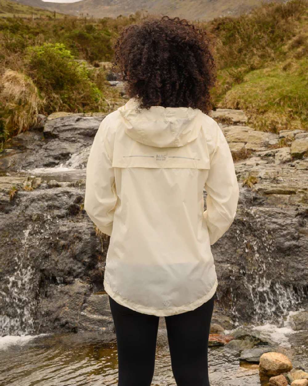 Ivory coloured Mac In A Sac Packable Origin Waterproof Jacket on blurry background 