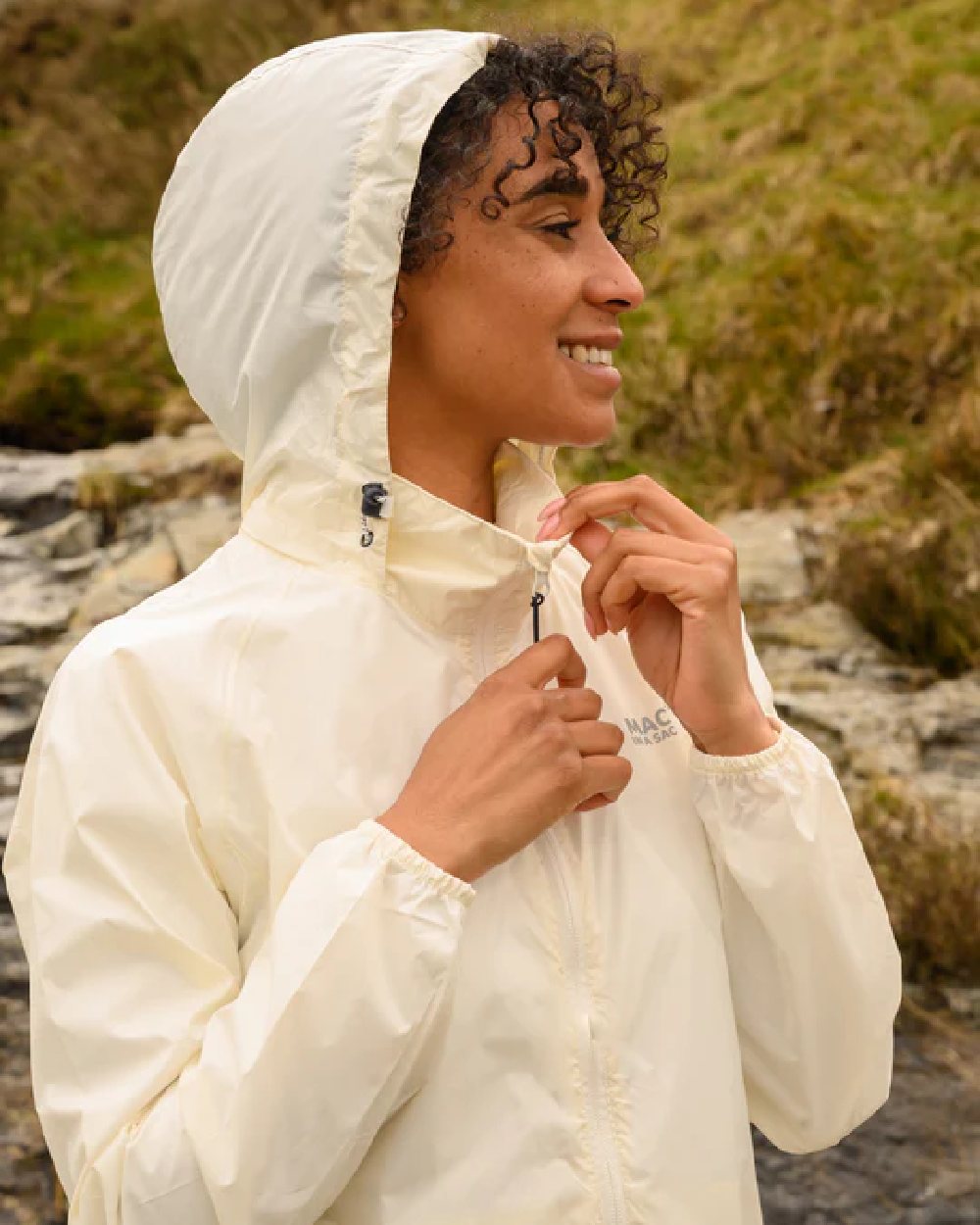 Ivory coloured Mac In A Sac Packable Origin Waterproof Jacket on blurry background 