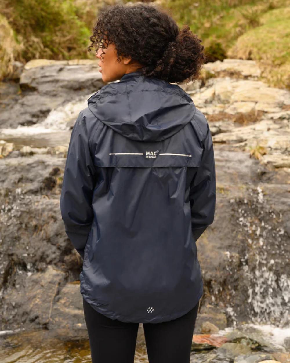 Navy coloured Mac In A Sac Packable Origin Waterproof Jacket on blurry background 