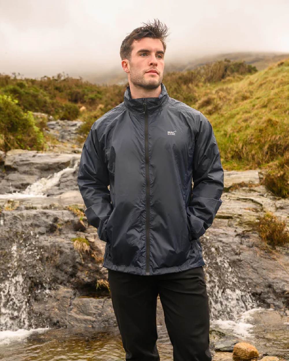 Navy coloured Mac In A Sac Packable Origin Waterproof Jacket on blurry background 