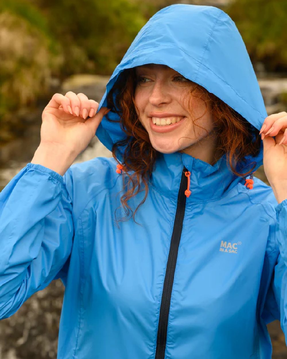 Ocean Blue coloured Mac In A Sac Packable Origin Waterproof Jacket on blurry background 