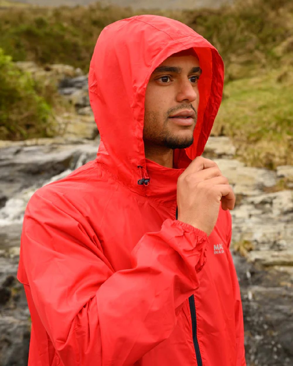 Red coloured Mac In A Sac Packable Origin Waterproof Jacket on blurry background 