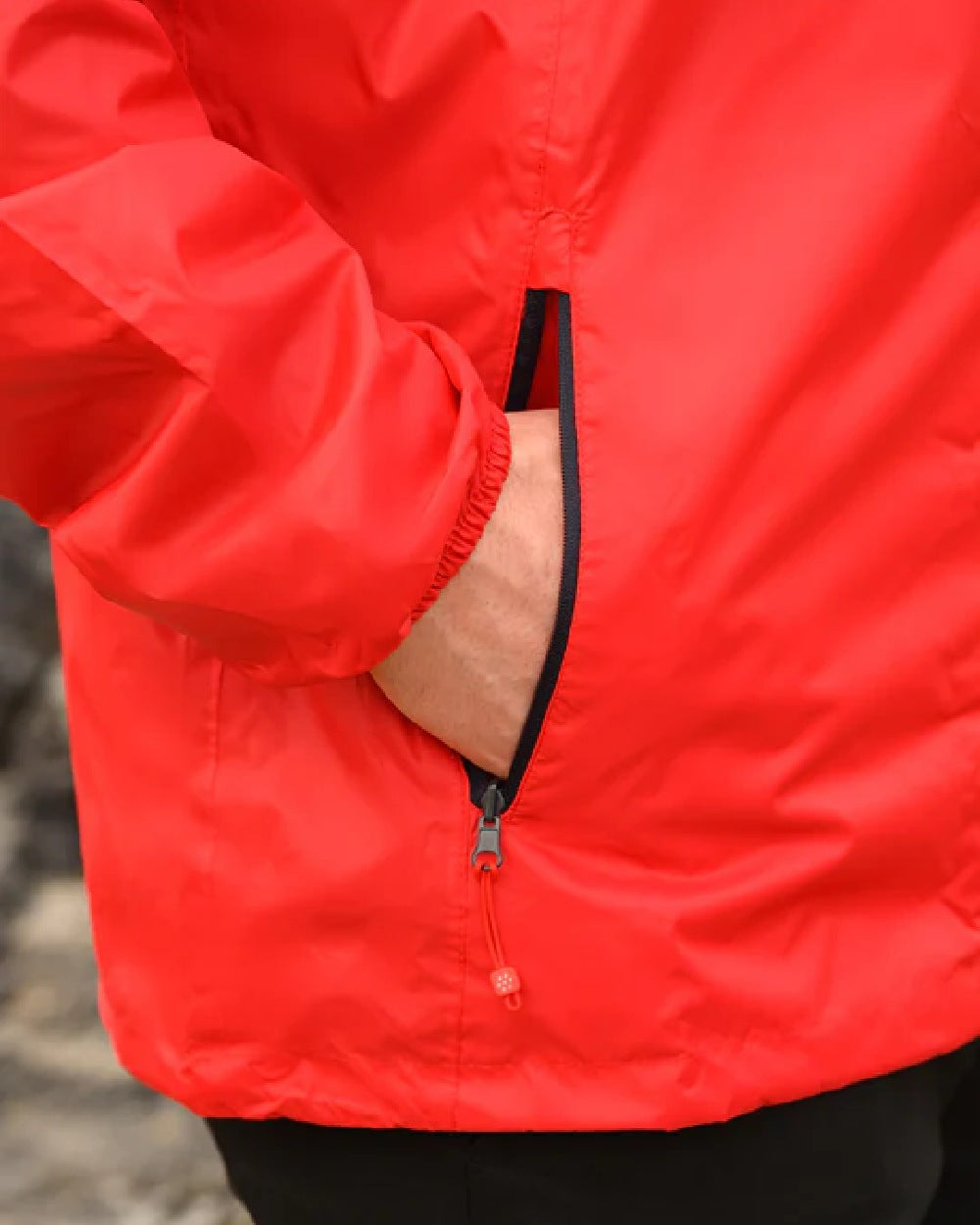 Red coloured Mac In A Sac Packable Origin Waterproof Jacket on blurry background 