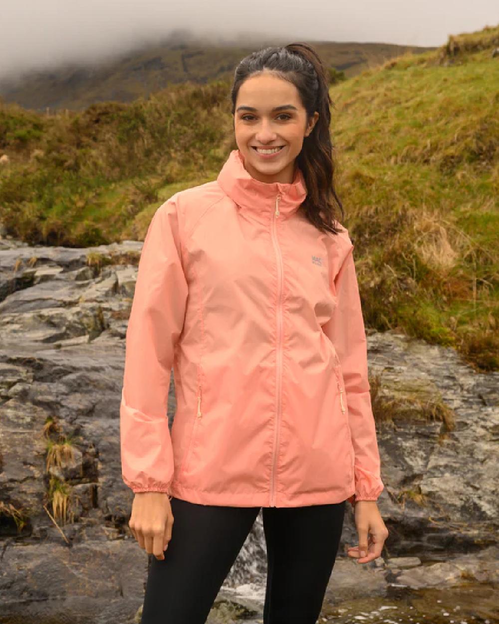 Soft Coral coloured Mac In A Sac Packable Origin Waterproof Jacket on blurry background 