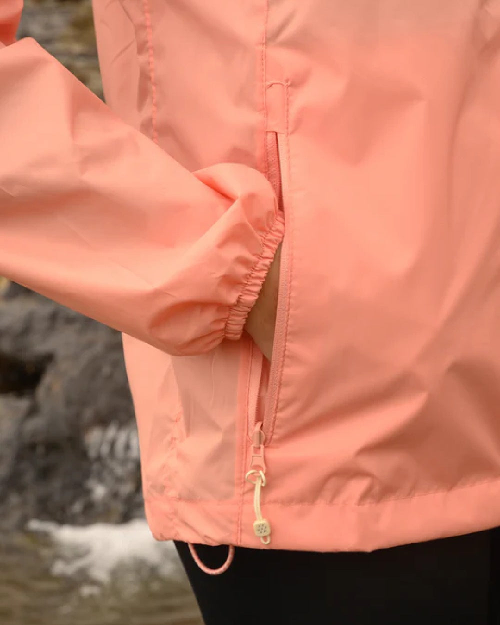 Soft Coral coloured Mac In A Sac Packable Origin Waterproof Jacket on blurry background 