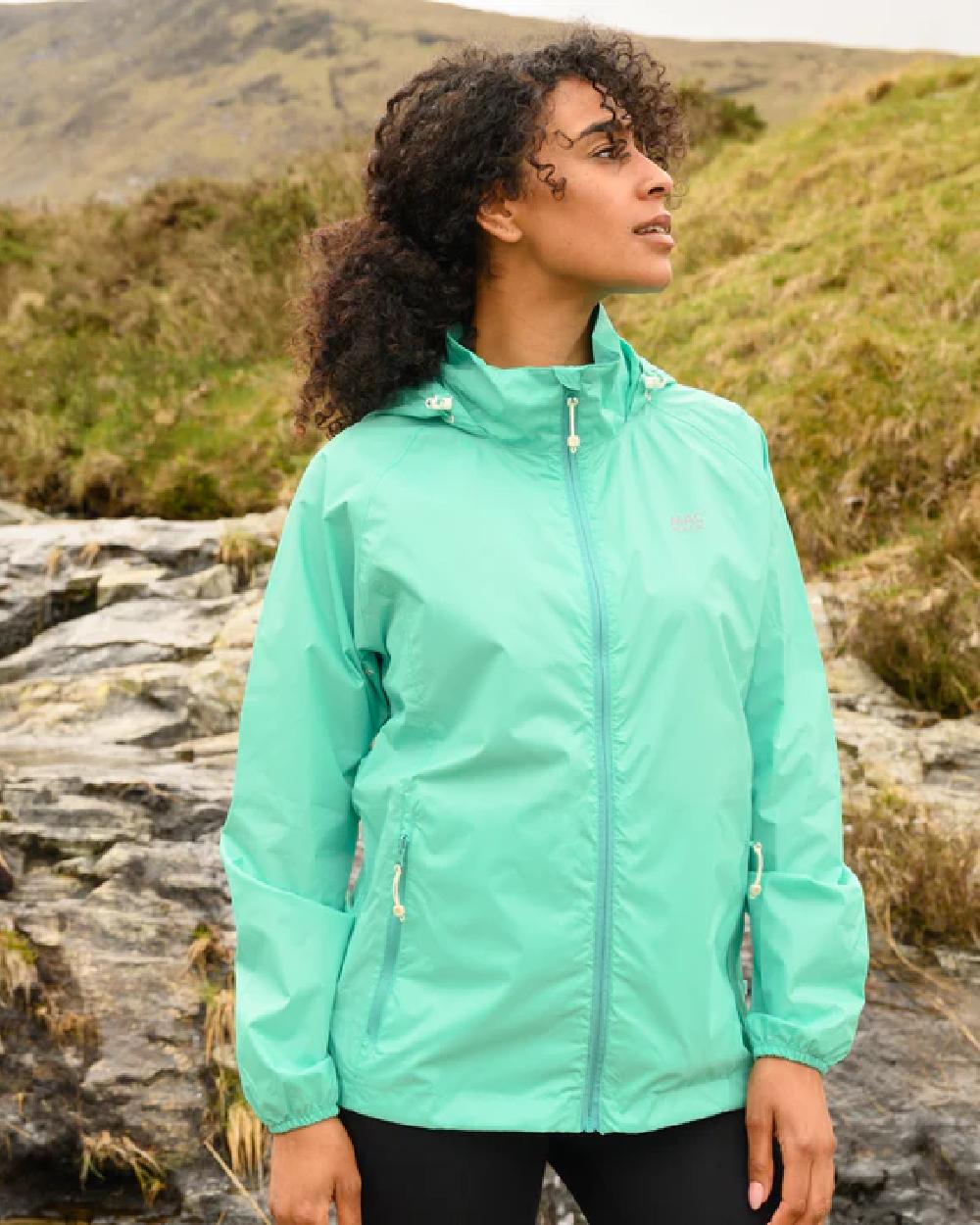 Tiffany Green coloured Mac In A Sac Packable Origin Waterproof Jacket on blurry background 