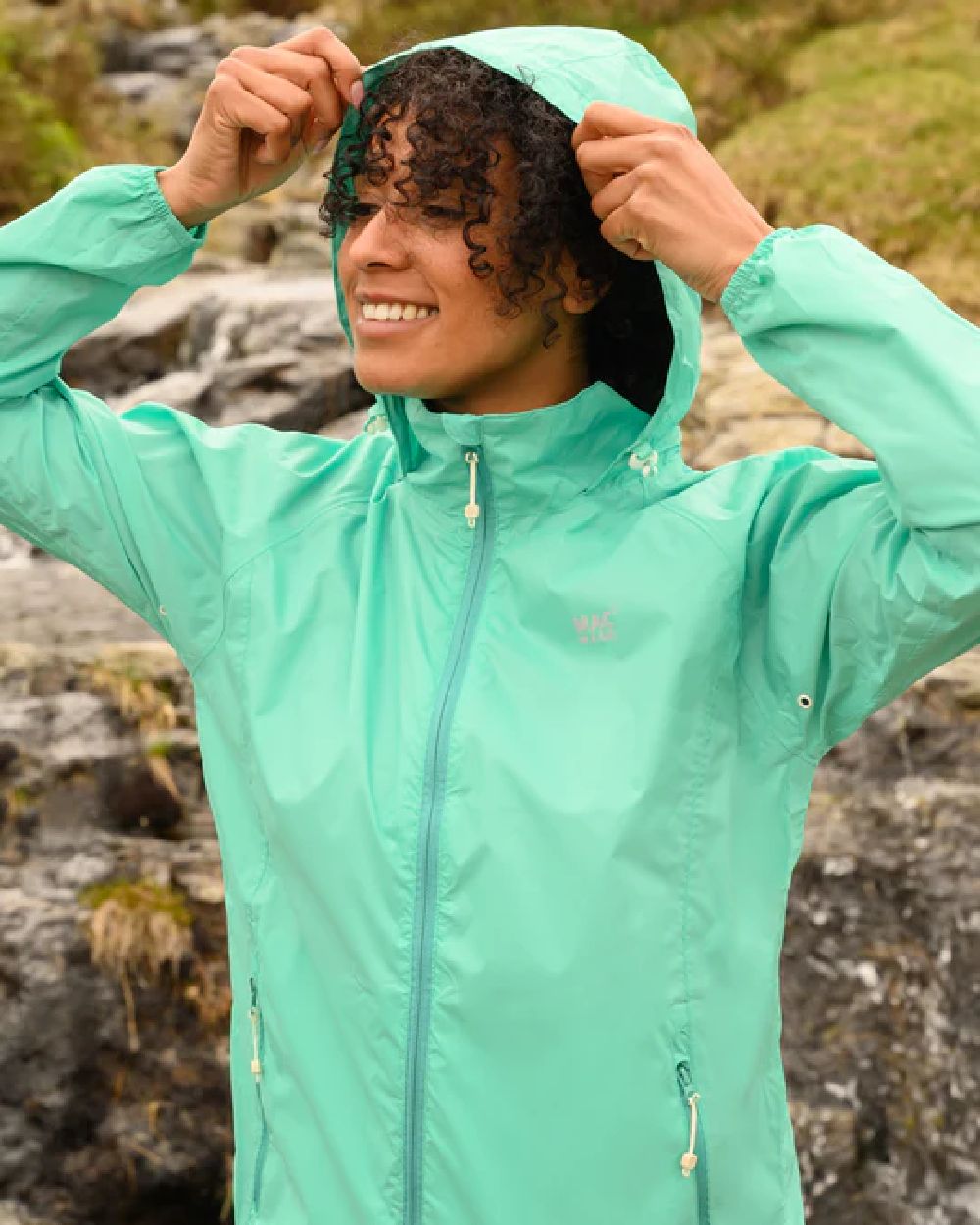 Tiffany Green coloured Mac In A Sac Packable Origin Waterproof Jacket on blurry background 