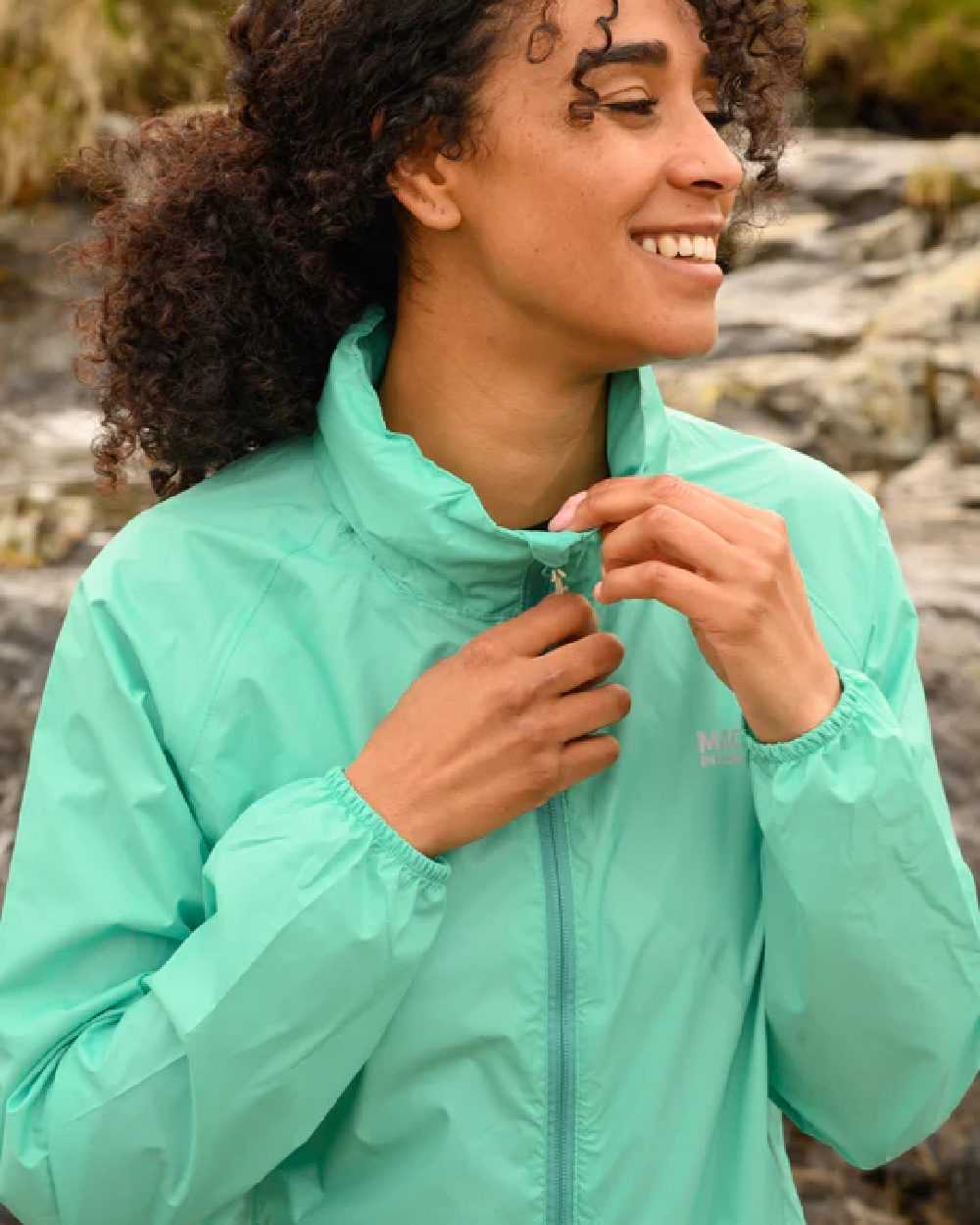 Tiffany Green coloured Mac In A Sac Packable Origin Waterproof Jacket on blurry background 