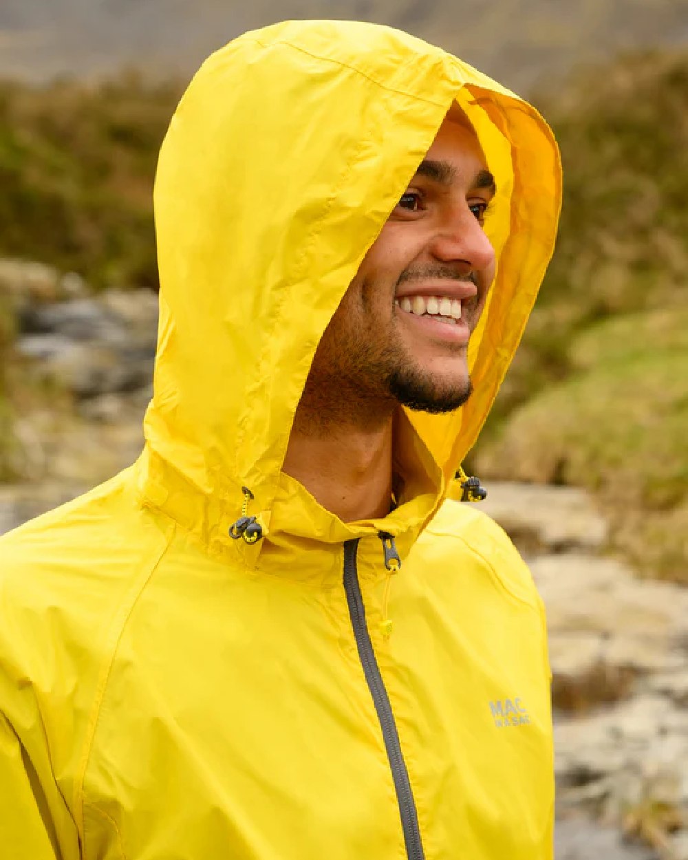 Yellow coloured Mac In A Sac Packable Origin Waterproof Jacket on blurry background 