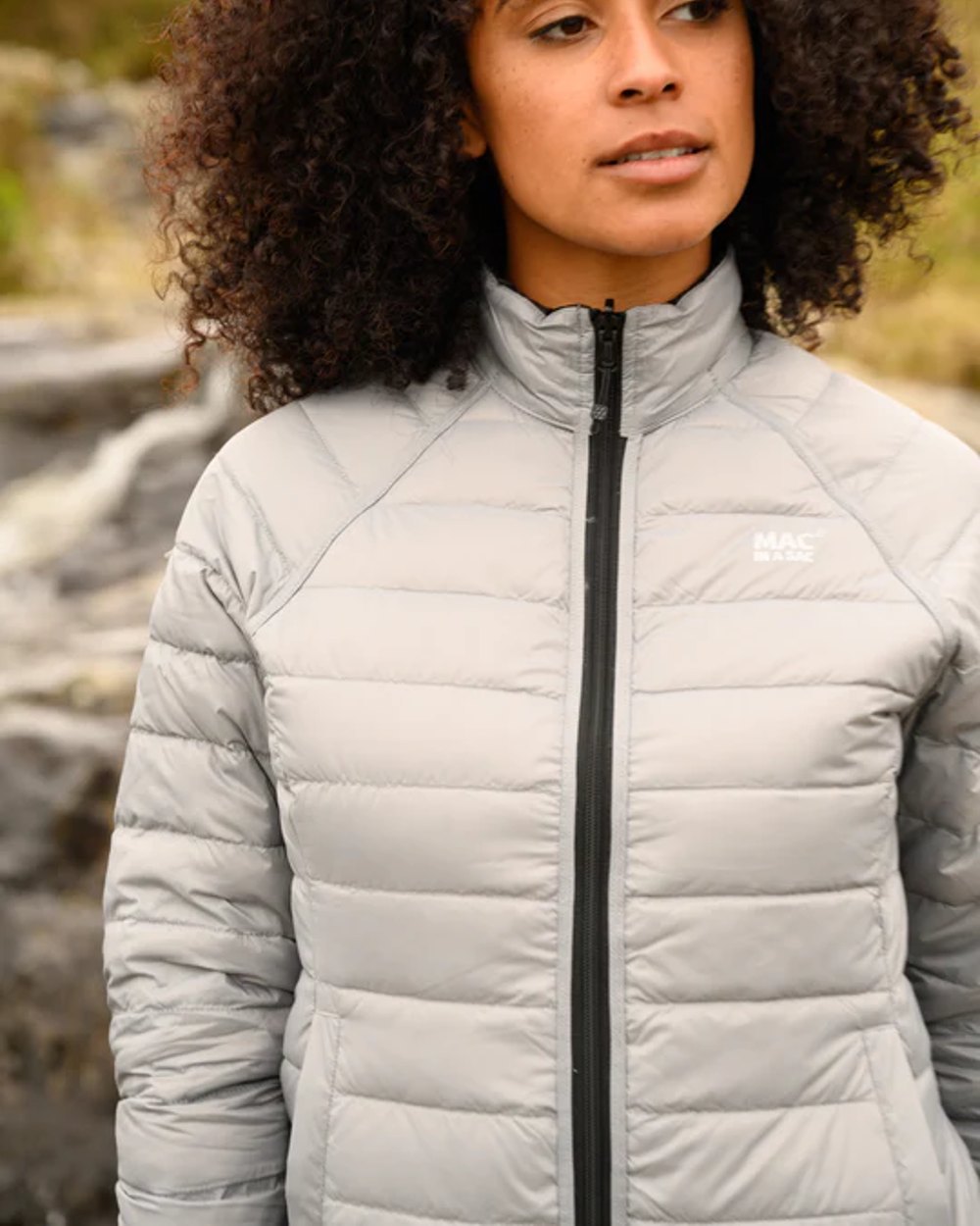 Black Grey coloured Mac In A Sac Packable Womens Down Jacket on blurry background 