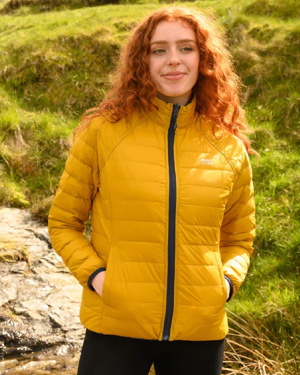 Navy Mustard coloured Mac In A Sac Packable Womens Down Jacket on blurry background 