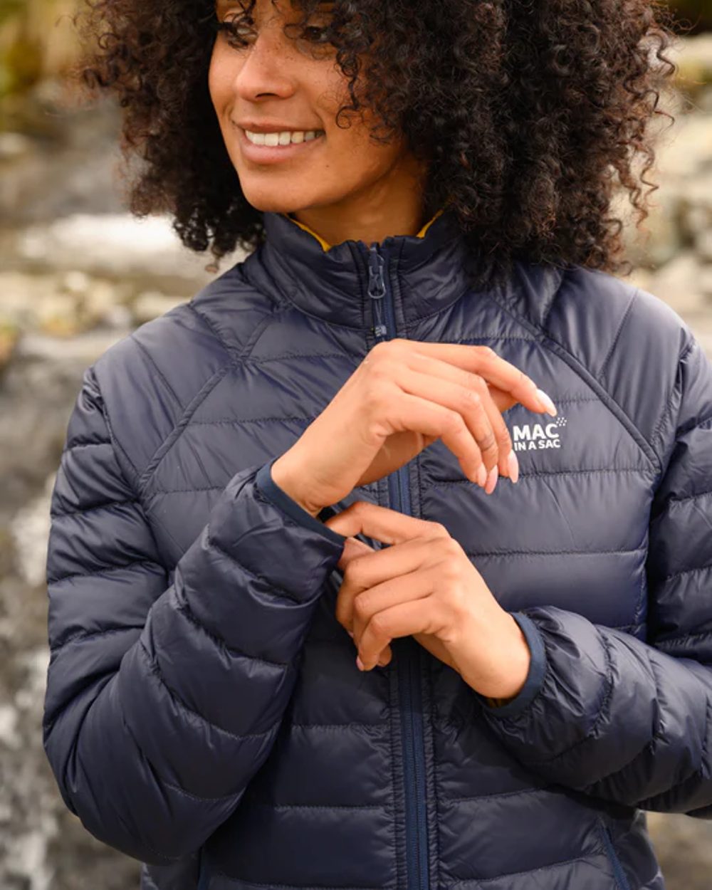 Navy Mustard coloured Mac In A Sac Packable Womens Down Jacket on blurry background 