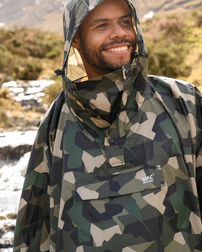Green Camo coloured Mac In A Sac Waterproof Poncho on a blurry mountain background 