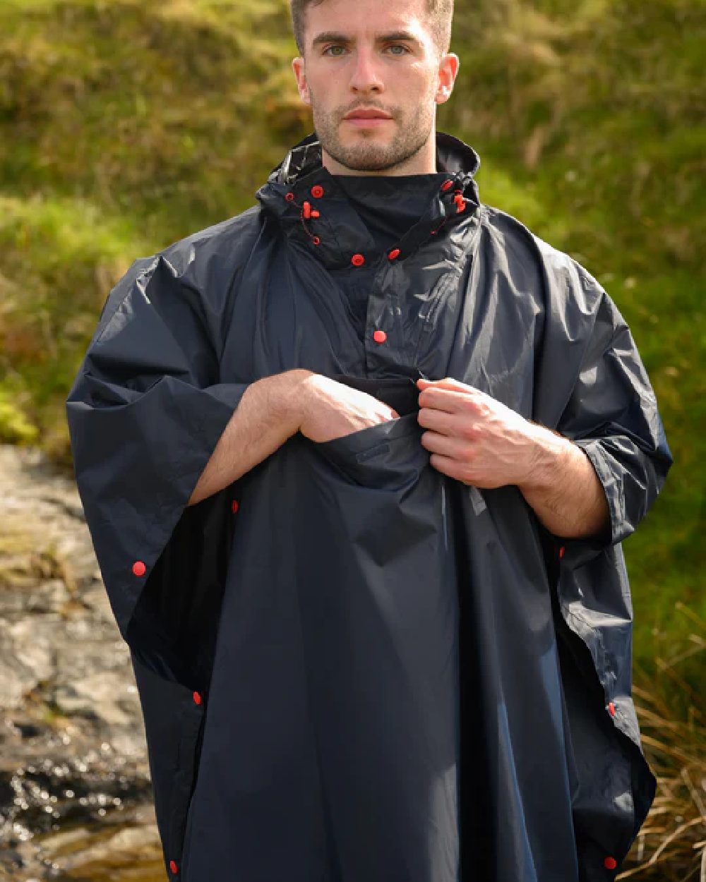 Navy coloured Mac In A Sac Waterproof Poncho on a blurry green background 
