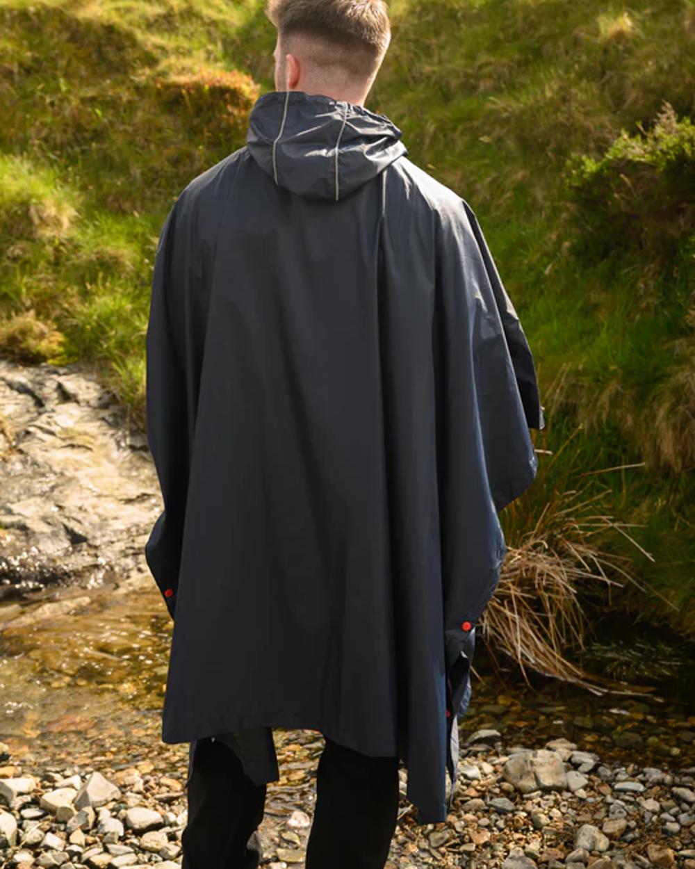 Navy coloured Mac In A Sac Waterproof Poncho on a blurry green background 