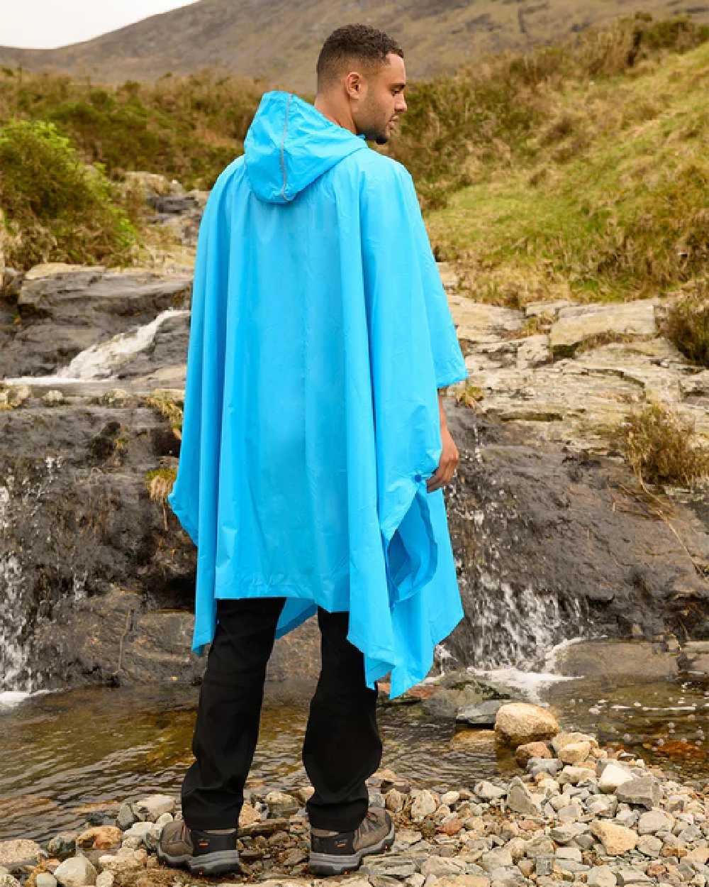Neon Blue coloured Mac In A Sac Waterproof Poncho on a mountain background 