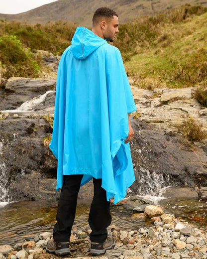 Neon Blue coloured Mac In A Sac Waterproof Poncho on a mountain background 