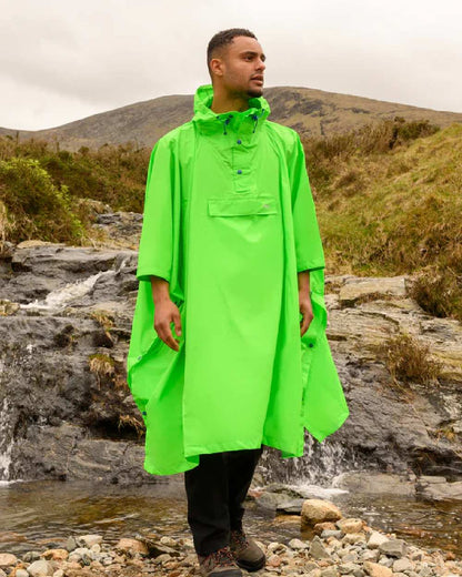 Neon green coloured Mac In A Sac Waterproof Poncho on a blurry mountain background 