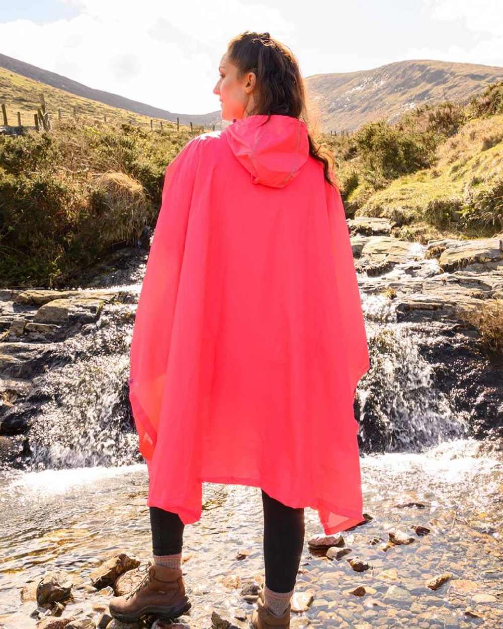 Neon Watermelon coloured Mac In A Sac Waterproof Poncho on a mountain background 