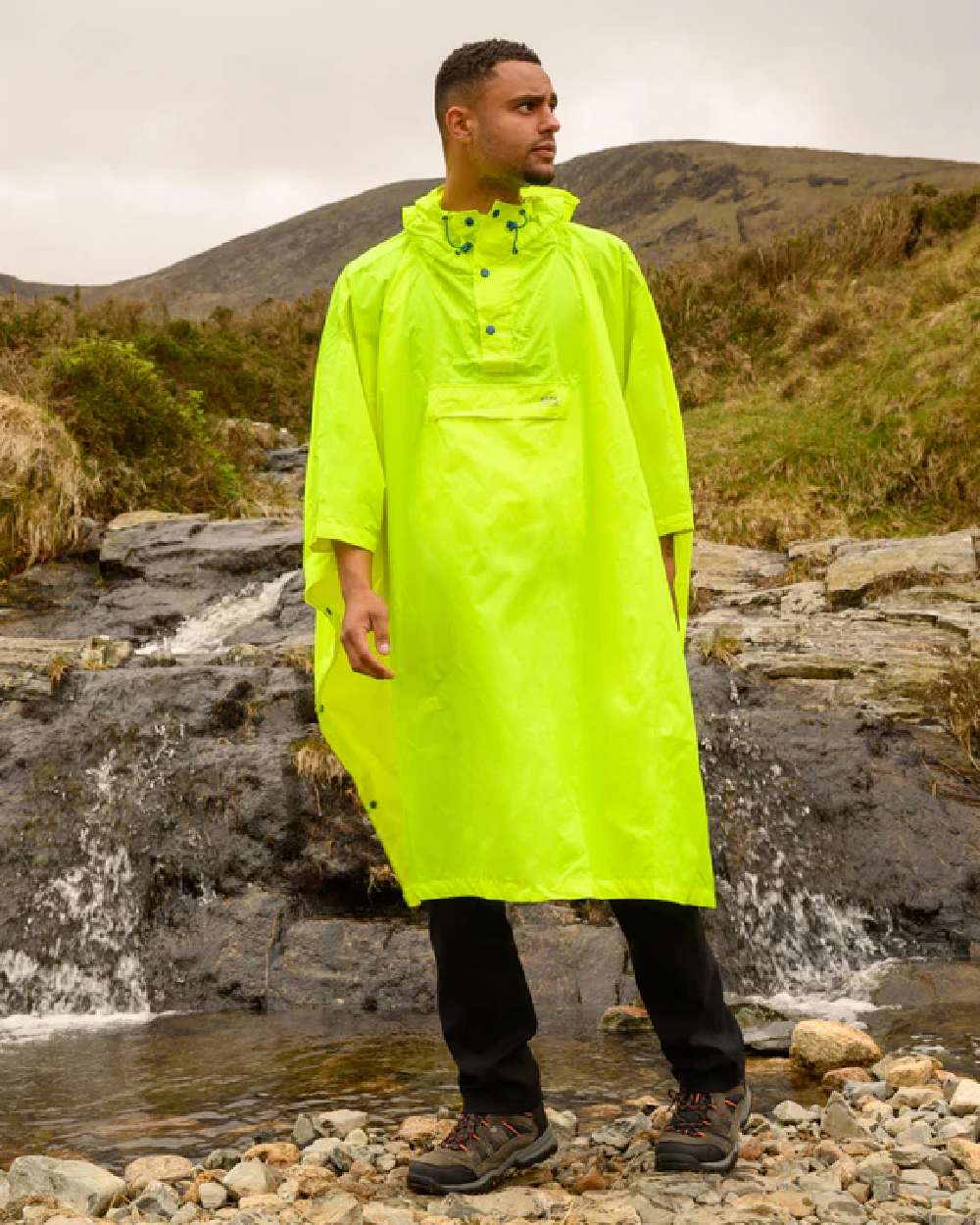 Neon Yellow coloured Mac In A Sac Waterproof Poncho on a mountain background 