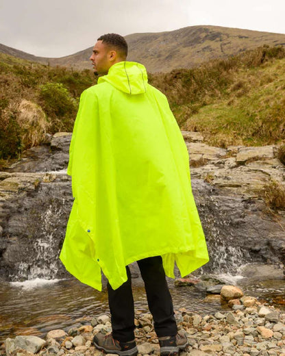 Neon Yellow coloured Mac In A Sac Waterproof Poncho on a mountain background 