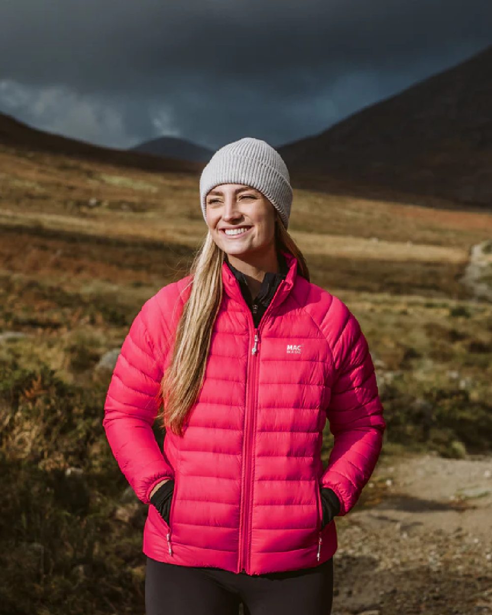 Watermelon coloured Mac In A Sac Womens Synergy Jacket on blurry mountain background 