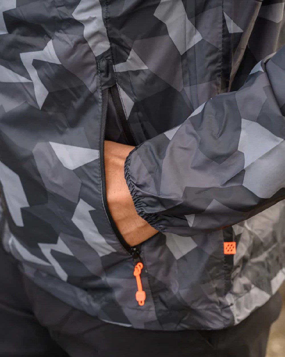 Black Camo coloured Mac In A Sac Packable Origin Camo Waterproof Jacket on blurry background 