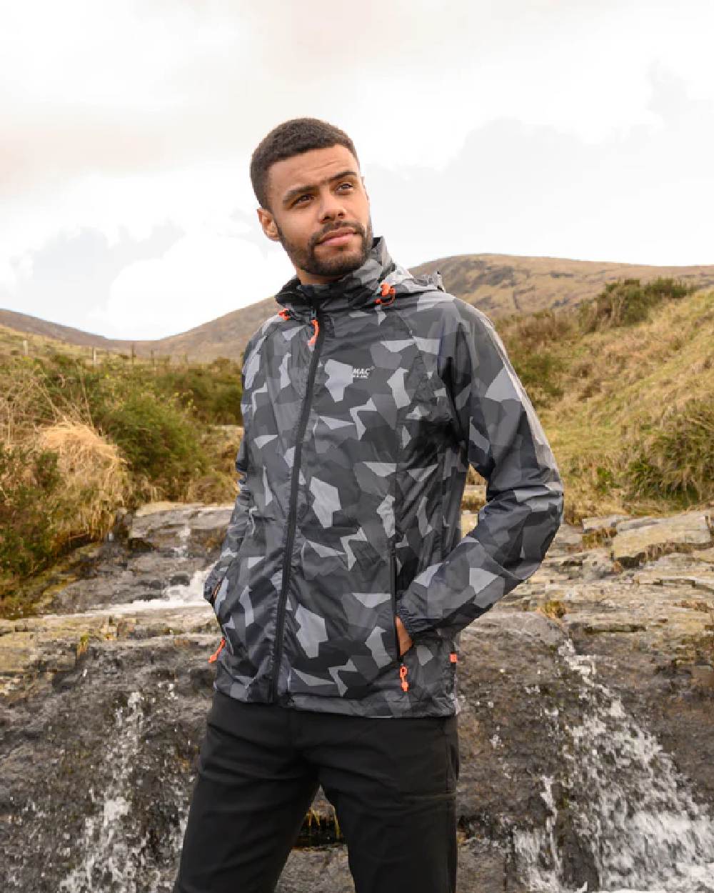 Black Camo coloured Mac In A Sac Packable Origin Camo Waterproof Jacket on blurry mountain background 