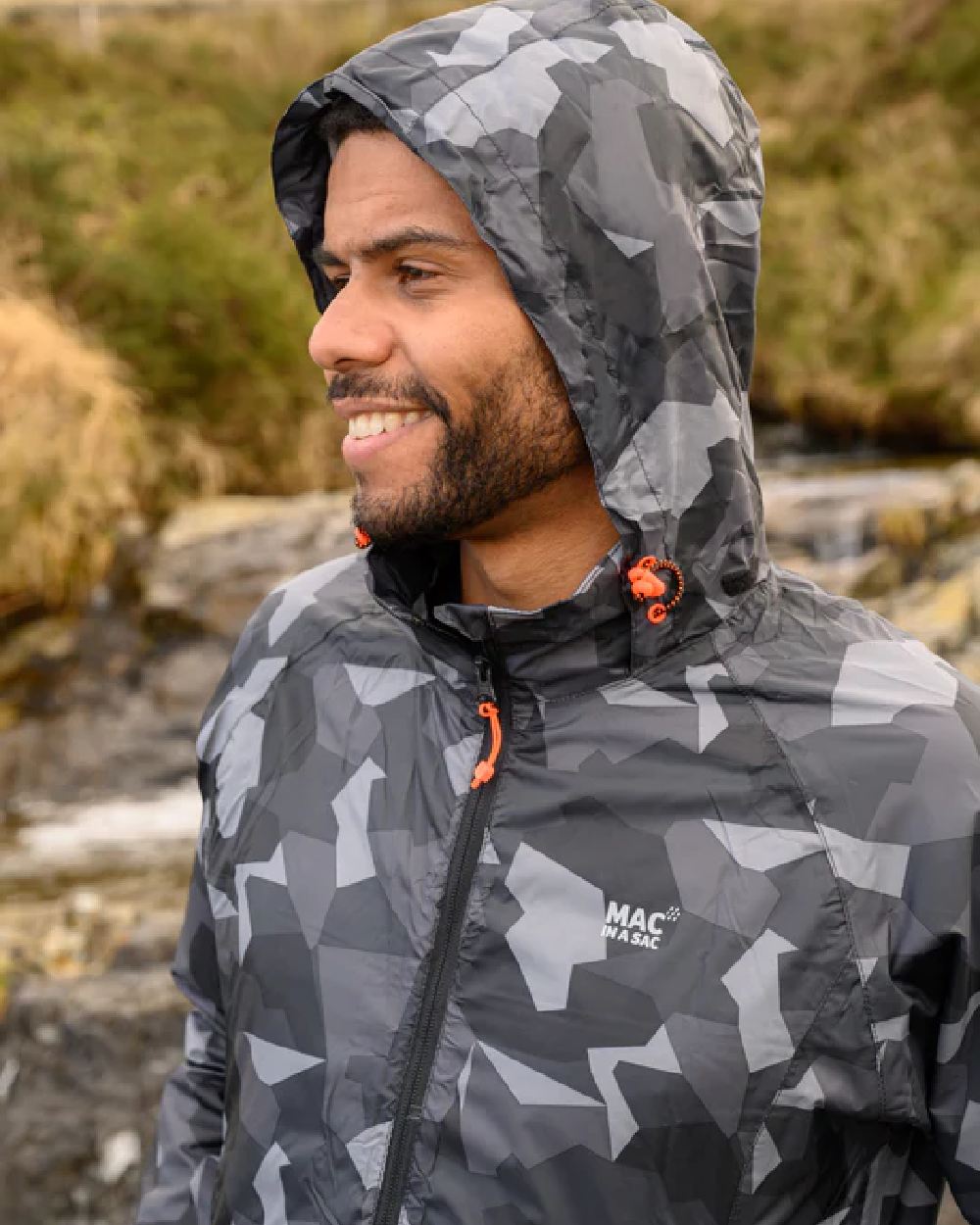 Black Camo coloured Mac In A Sac Packable Origin Camo Waterproof Jacket on blurry background 