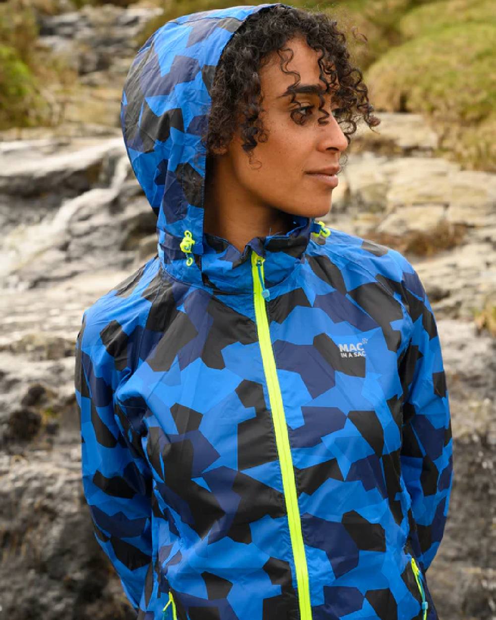 Blue Camo coloured Mac In A Sac Packable Origin Camo Waterproof Jacket on blurry background 