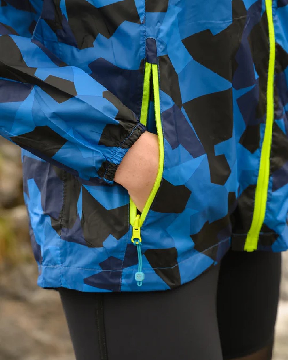 Blue Camo coloured Mac In A Sac Packable Origin Camo Waterproof Jacket on blurry background 