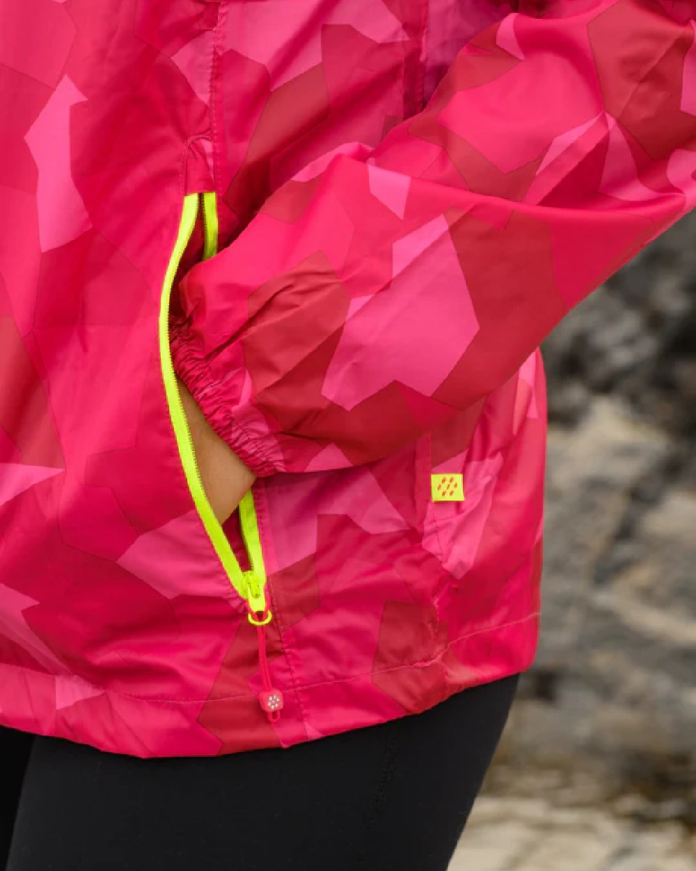 Pink Camo coloured Mac In A Sac Packable Origin Camo Waterproof Jacket on blurry background 