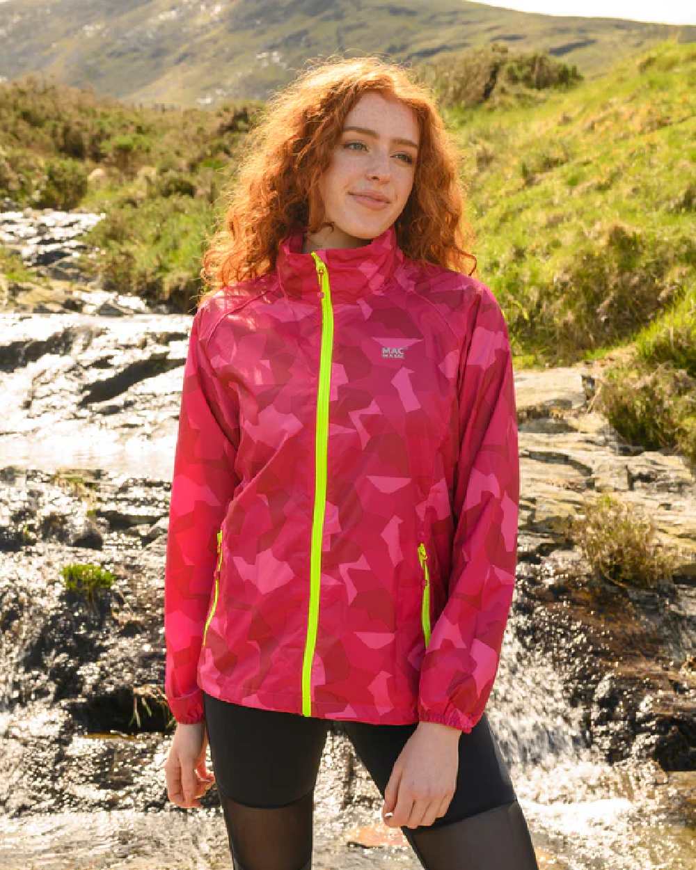 Pink Camo coloured Mac In A Sac Packable Origin Camo Waterproof Jacket on blurry background 
