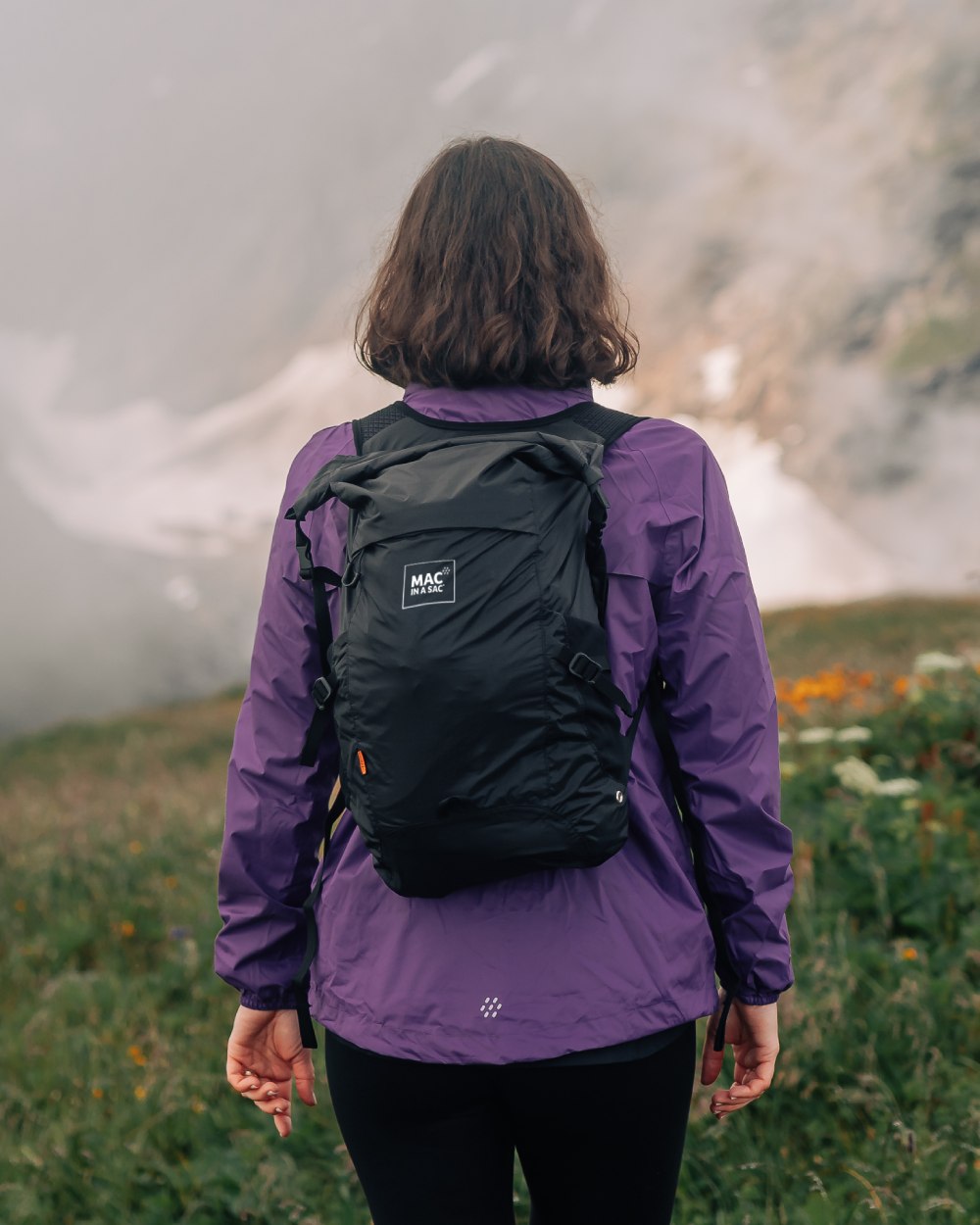 Jet Black coloured Mac In A Sac Travelite Packable Waterproof Backpack on forest background 
