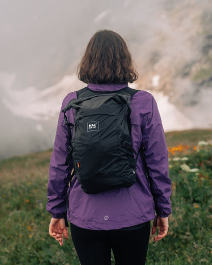 Jet Black coloured Mac In A Sac Travelite Packable Waterproof Backpack on forest background 