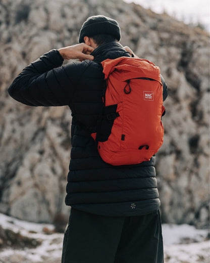 Burnt Orange coloured Mac In A Sac Travelite Packable Waterproof Backpack on forest background 